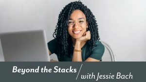 Feature Image for Biblioboard, Pressbooks and the Indie Author Project: A smiling woman sitting at a desk with a laptop. "Beyond the Stacks with Jessie Bach" is written in white text on a grey background below the image.
