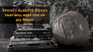 Spooky Alberta Books That Will Keep You Up All Night: A greyscale photo of a stack of books beside a pumpkin.